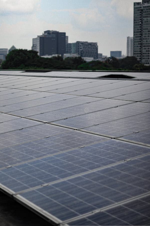 Closeup of the rows of the solar panels under the cloudy blue sky in a city stock photo