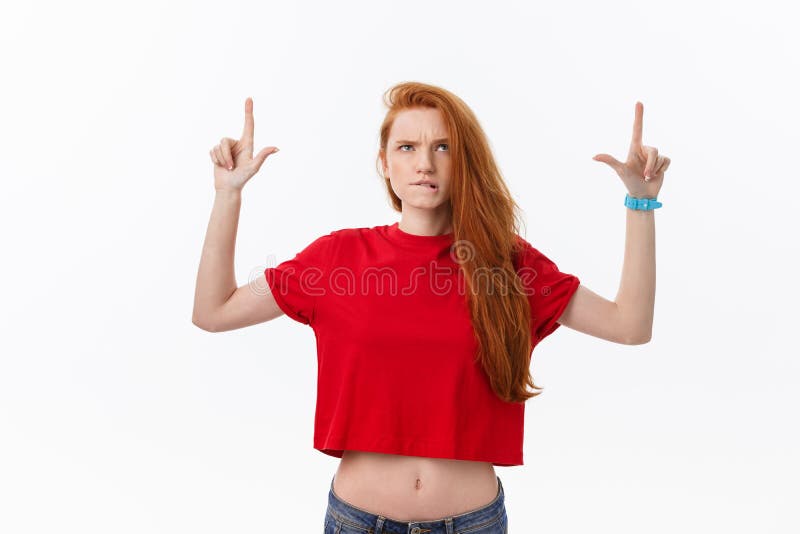 Closeup of serious strict young woman wears red shirt looks stressed and pointing up with finger isolated over white