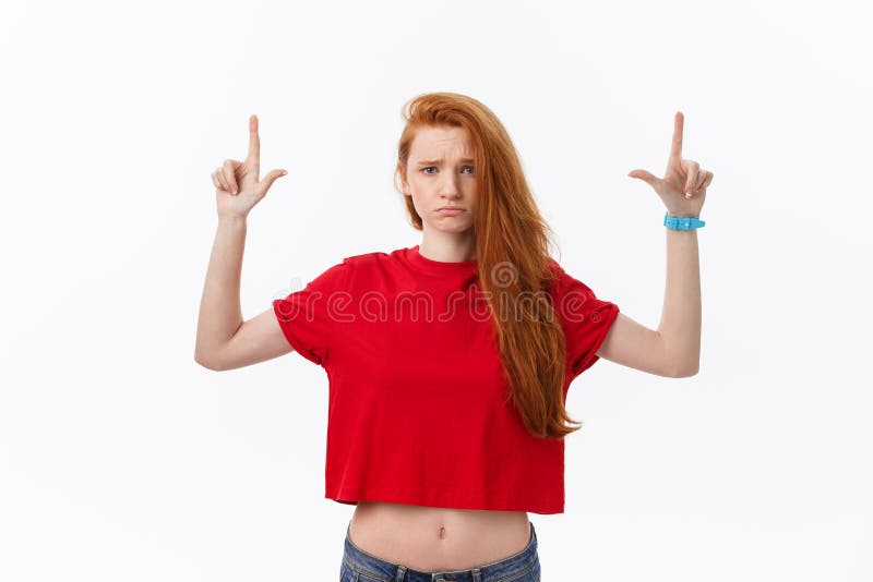 Closeup of serious strict young woman wears red shirt looks stressed and pointing up with finger isolated over white