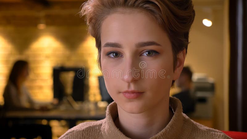 Closeup shoot of young attractive caucasian employee looking straight at camera on the workplace indoors in the office royalty free stock image Closeup shoot of young attractive caucasian employee looking straight at camera on the workplace indoors in the office royalty free stock image