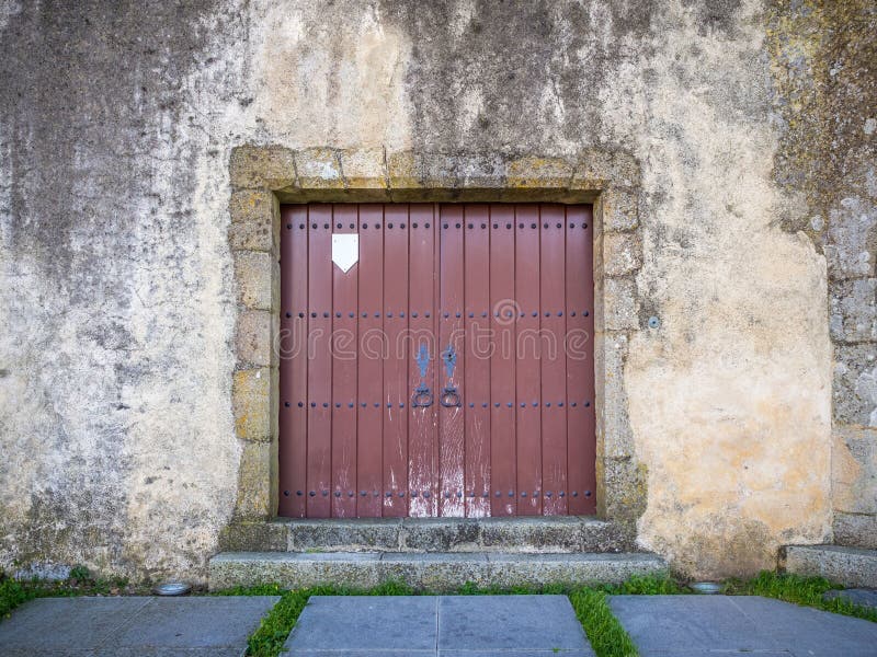 Closeup shot of a brown gate door in a damaged wall of an old building