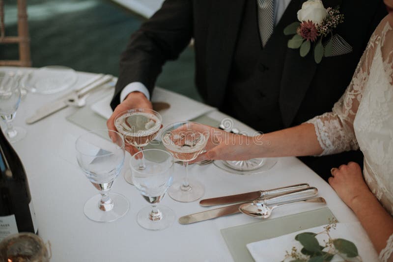 Closeup shot of a female and male holding two glasses of champagne on a wedding table stock images Closeup shot of a female and male holding two glasses of champagne on a wedding table stock images