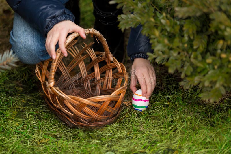 Closeup shot of girl putting colorful Easter egg in the basket