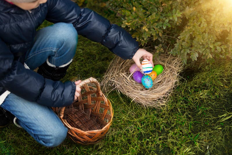 Closeup shot of little girl putting painted egg in basket