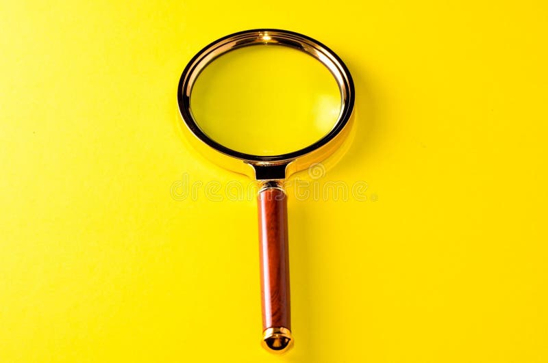 Closeup shot of magnifying glass on a yellow background royalty free stock photo