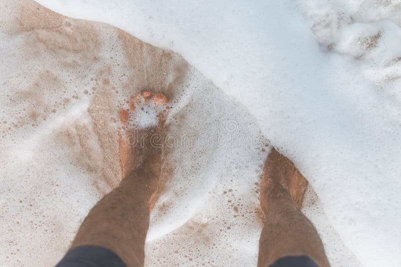 Closeup shot of male`s feet in ocean water