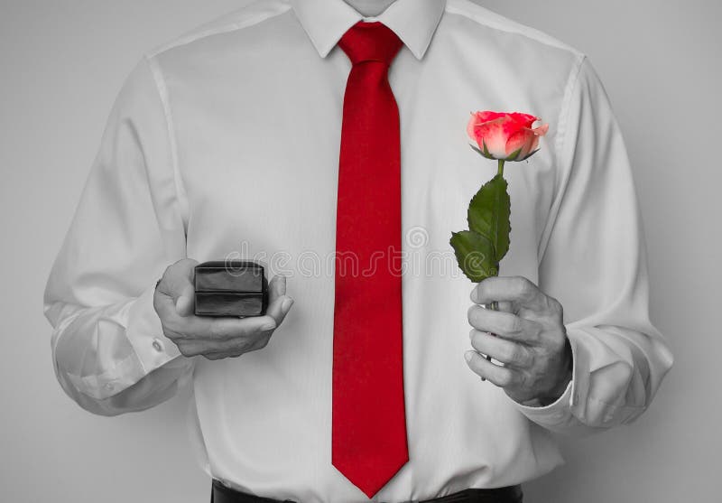 Closeup shot of man proposing with a rose and engagement ring in black and white. Tie and rose isolated with color. royalty free stock images Closeup shot of man proposing with a rose and engagement ring in black and white. Tie and rose isolated with color. royalty free stock images