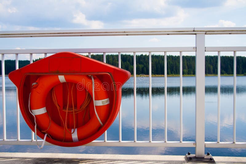 Closeup shot of a red lifebuoy hanged on the white railing of a bridge stock photos