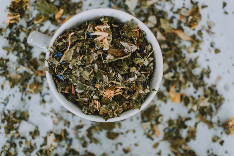 Closeup Shot Of A White Bowl Full Of Dried Leaves On A White Blurred Background