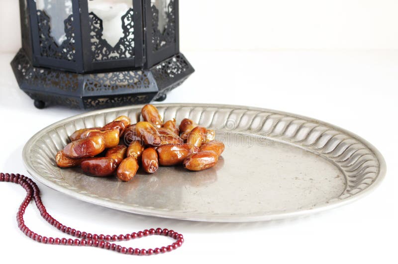Closeup of silver plate with date fruits, prayer beads and ornamental dark Moroccan, Arabic lantern on the white table stock photos Closeup of silver plate with date fruits, prayer beads and ornamental dark Moroccan, Arabic lantern on the white table stock photos