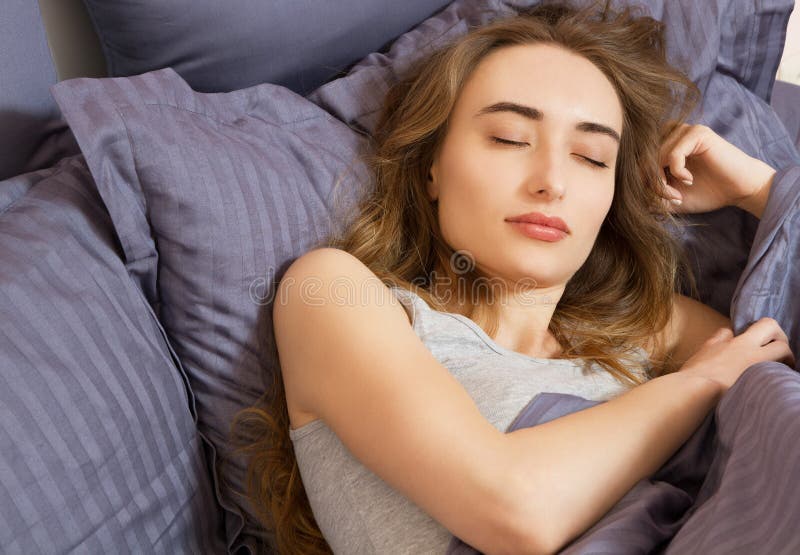 Closeup - Sleep. Young Woman Sleeping In Bed. Portrait Of Beautiful Female Resting On Comfortable Bed With Pillows In Bedding In