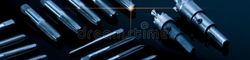 Closeup straight flute tap tip and hole saw on dark background. Industrial tapping tools. Carbide tip metal cutter. Metalworking royalty free stock image Closeup straight flute tap tip and hole saw on dark background. Industrial tapping tools. Carbide tip metal cutter. Metalworking royalty free stock image