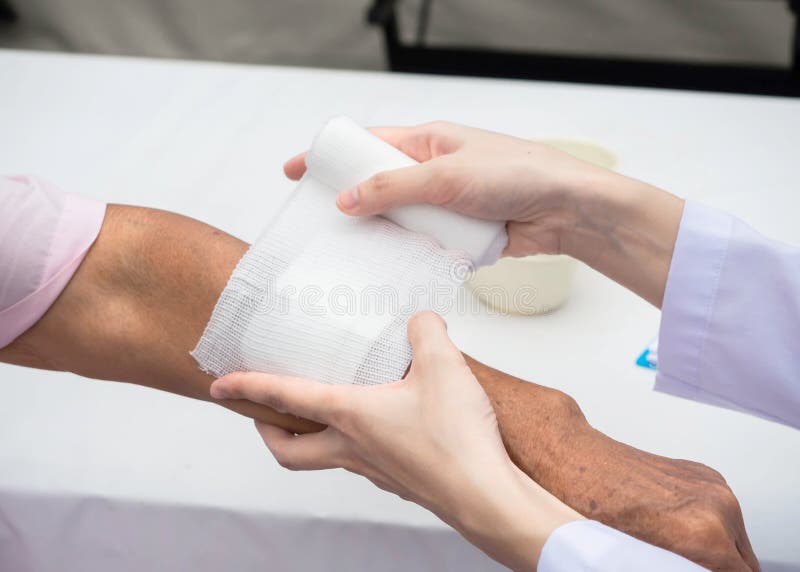 Closeup-sårbehandling En äldre person Läkare som använder bandage på äldre kvinnors arm hemma, med handskar för att skydda