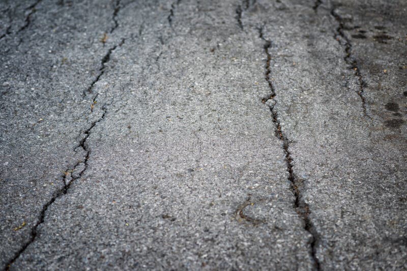 Closeup textured background of cracks on asphault rural road. damaged collapsed street after earthquake. Closeup textured background of cracks on asphault rural road. damaged collapsed street after earthquake