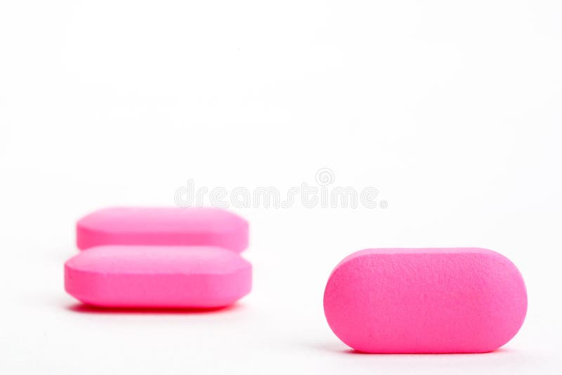 Closeup of three pink pills, isolated