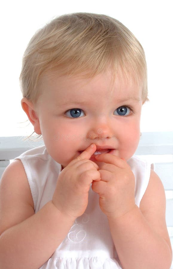 Closeup of toddler girl sitting on chair, smiling, in white dress, on white background