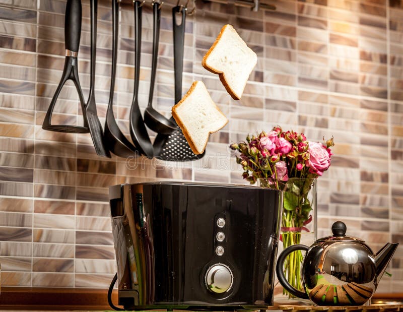 Closeup of two slices of bread popping out of toaster on kitchen