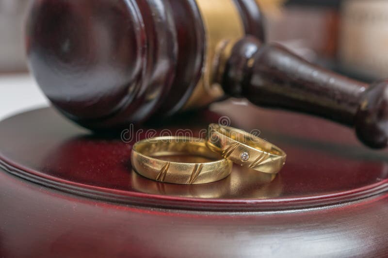 Closeup view on golden rings and gavel in background. Divorce concept stock photography