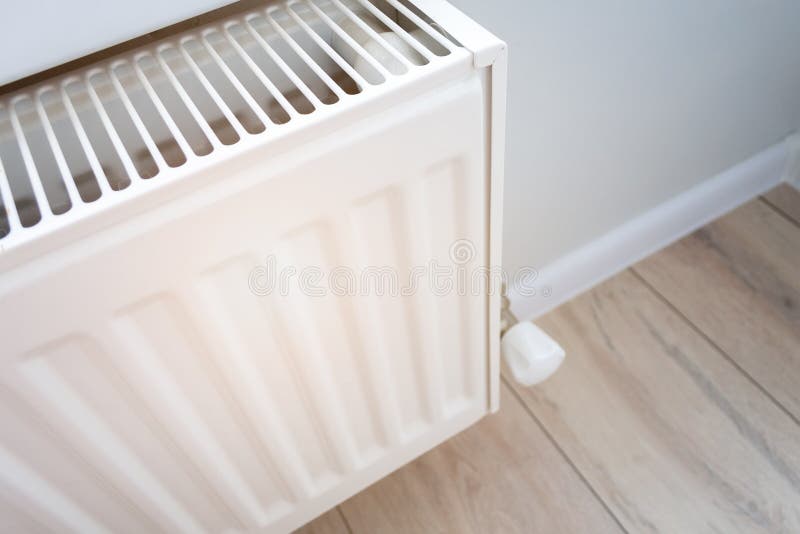 Closeup view of a home heating radiator in a living room with wooden floor and light wall stock photo
