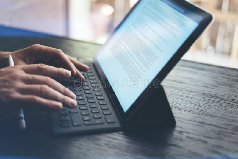 Closeup view of male hands typing on electronic tablet keyboard-dock station. Business text information on device screen stock image Closeup view of male hands typing on electronic tablet keyboard-dock station. Business text information on device screen stock image