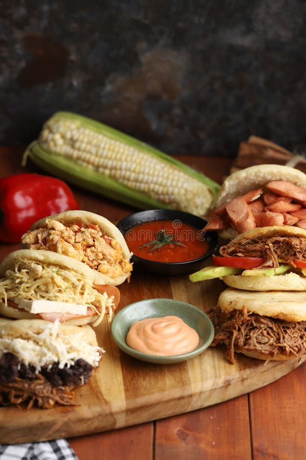Closeup View of Six Differently Flavored Arepas Served with Sauce and a
