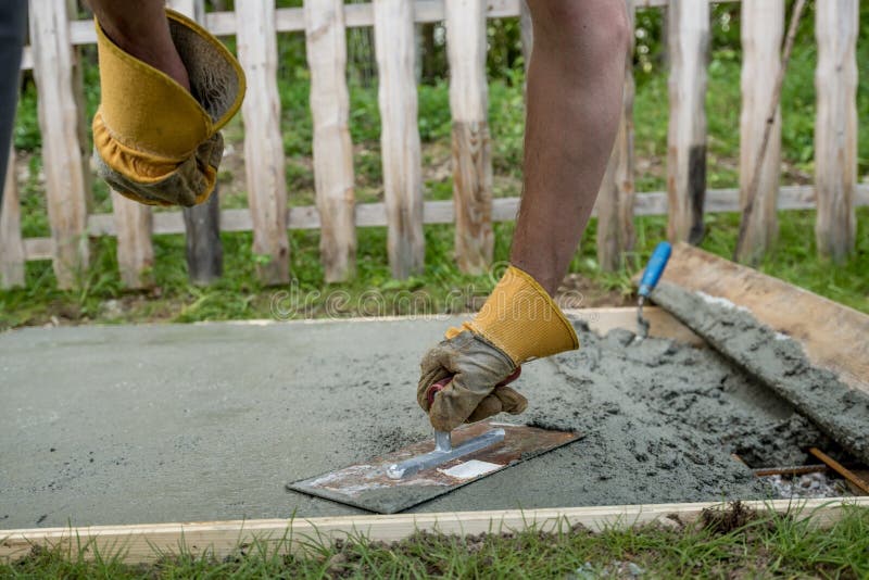 Man Leveling the Cement in a Backyard at Home Using a Wooden Plank
