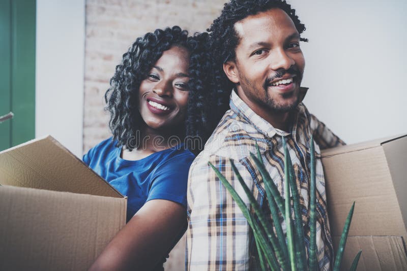 Closeup view of Young black african man and his girlfriend moving boxes into new house together and making a beautiful