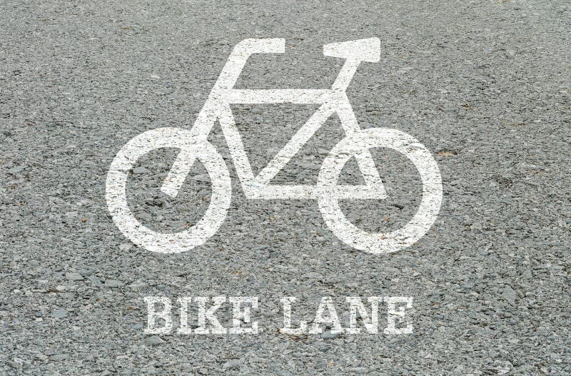 Closeup white painted of bicycle sign in bike lane at the street floor in park textured background