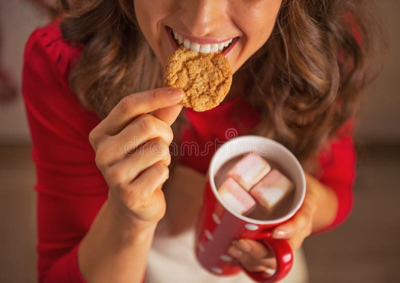 Closeup on woman drinking chocolate and eating christmas cookie