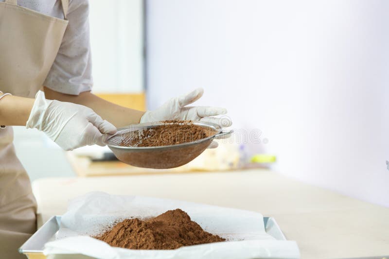 Closeup of woman, female baker hands while using flour sifter to make cocoa to bake homemade cake or bakery first time, learning stock photos