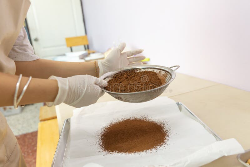 Closeup of woman, female baker hands while using flour sifter to make cocoa to bake homemade cake or bakery first time, learning stock photos