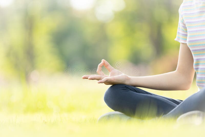 Closeup of woman hand meditating in yoga pose or lotus position on green grass,child girl practicing yoga meditation in nature