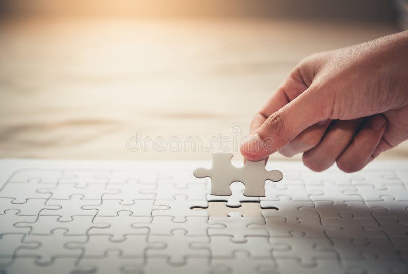 Closeup of woman hand fulfill the last piece of jigsaw puzzle to complete.,Business solutions, success mission concept. Closeup of woman hand fulfill the last piece of jigsaw puzzle to complete.,Business solutions, success mission concept.