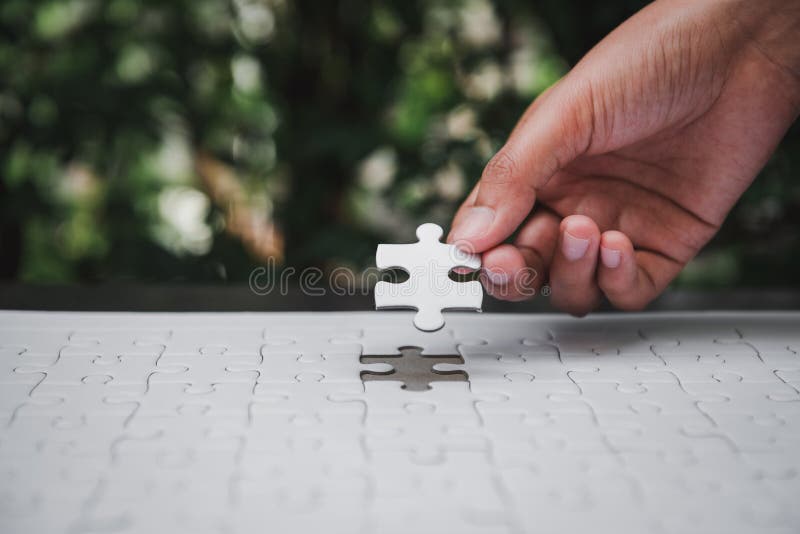Closeup of woman hands fulfill the last piece of jigsaw puzzle to complete.,Business solutions, success mission concept.