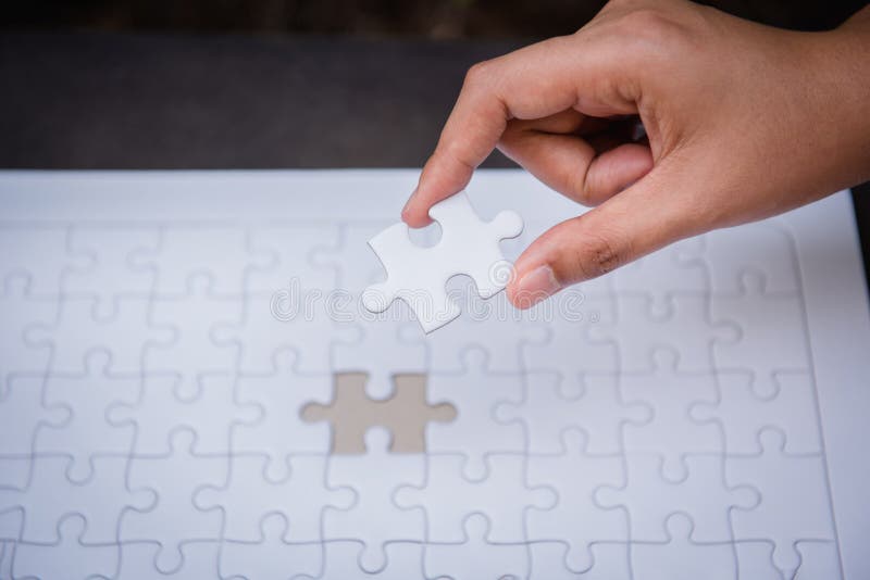 Closeup of woman hands fulfill the last piece of jigsaw puzzle to complete.,Business solutions, success mission concept.