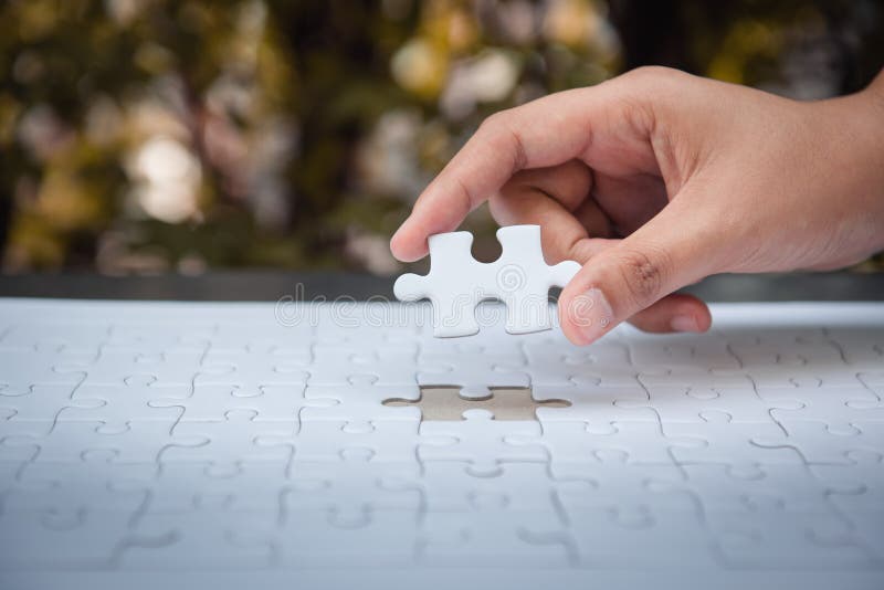 Closeup of woman hands fulfill the last piece of jigsaw puzzle to complete.,Business solutions, success mission concept
