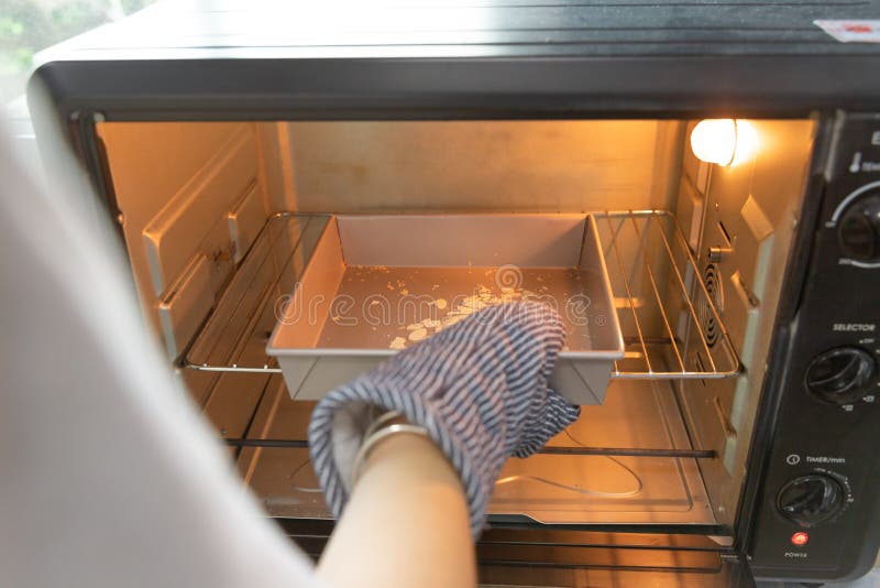 Closeup woman hands with oven mitt is , preparing, bringing bakery material to oven to bake homemade cake or bakery first time royalty free stock photos