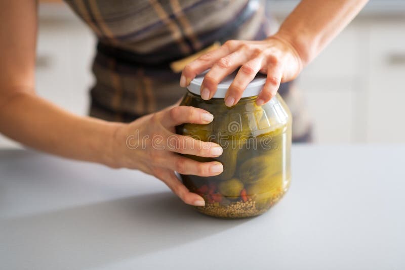 Closeup on woman opening jar of pickled cucumbers. Closeup on young housewife opening jar of pickled cucumbers stock images