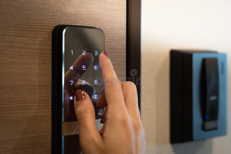 Closeup of a woman`s finger entering password code on the smart digital touch screen keypad entry door lock in front of the room