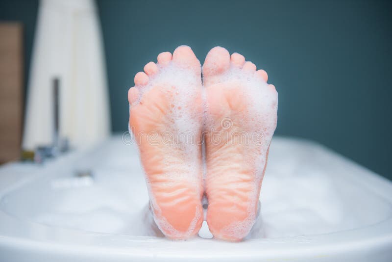 Closeup of woman`s foot on the edge of a bath with foam