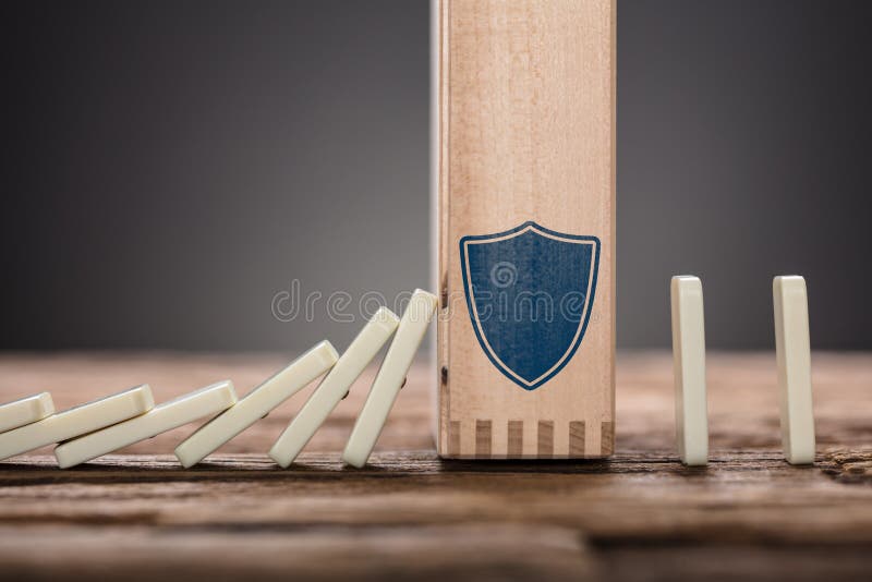 Block With Shield Symbol Amidst Falling Domino Pieces stock image