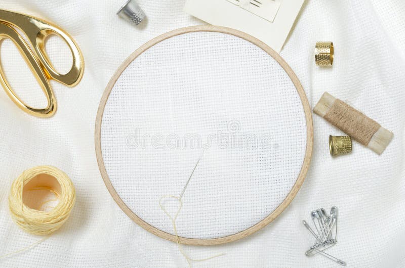 Closeup of wooden embroidery frames, scissors, threads, thimbles, needles, and clean white fabric for embroidering.Empty space for