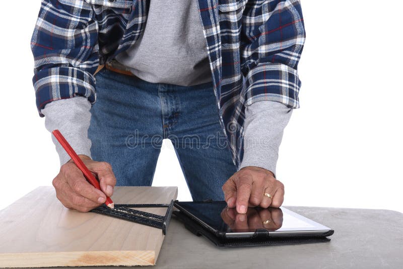 Closeup of a woodworker marking a cut line on a board as he checks specs on his tablet computer royalty free stock photo Closeup of a woodworker marking a cut line on a board as he checks specs on his tablet computer royalty free stock photo