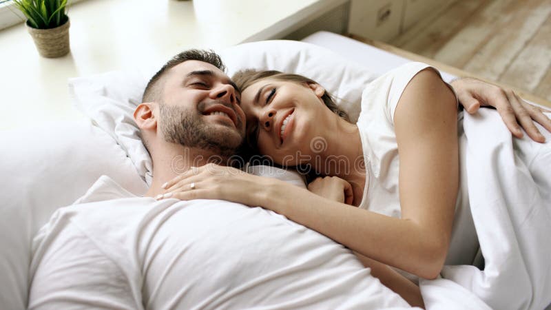 Closeup of young beautiful and loving couple talk and hug into bed while waking up in the morning. stock photos Closeup of young beautiful and loving couple talk and hug into bed while waking up in the morning. stock photos