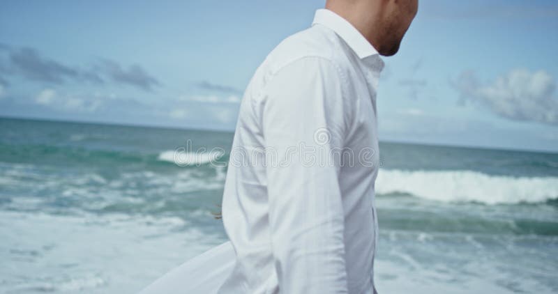 Closeup young couple have a romantic time beside the seaside they walking through the black sand they have the bare feet