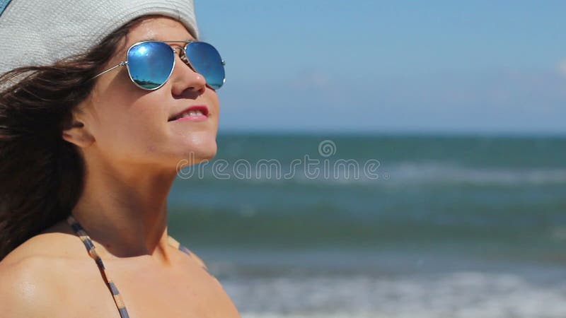 Closeup of young female in sunglasses enjoying relax on sunny beach at seaside