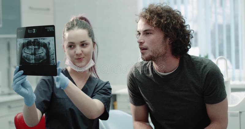 Closeup young man at dentist have a friendly conversation with his doctor , young dentist explain carefully his results