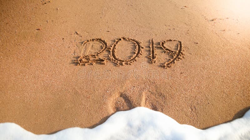 Closeupbild av havsvågen som ut tvättar 2019 nummer för nytt år från våt sand på havsstranden begrepp av det nya året, jul royaltyfri bild Closeupbild av havsvågen som ut tvättar 2019 nummer för nytt år från våt sand på havsstranden begrepp av det nya året, jul royaltyfri bild