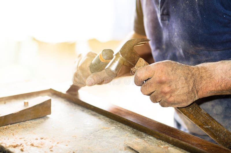 Closeupen av en snickare räcker arbete med en stämjärn och en hammare på träarbetsbänken arkivfoton Closeupen av en snickare räcker arbete med en stämjärn och en hammare på träarbetsbänken arkivfoton