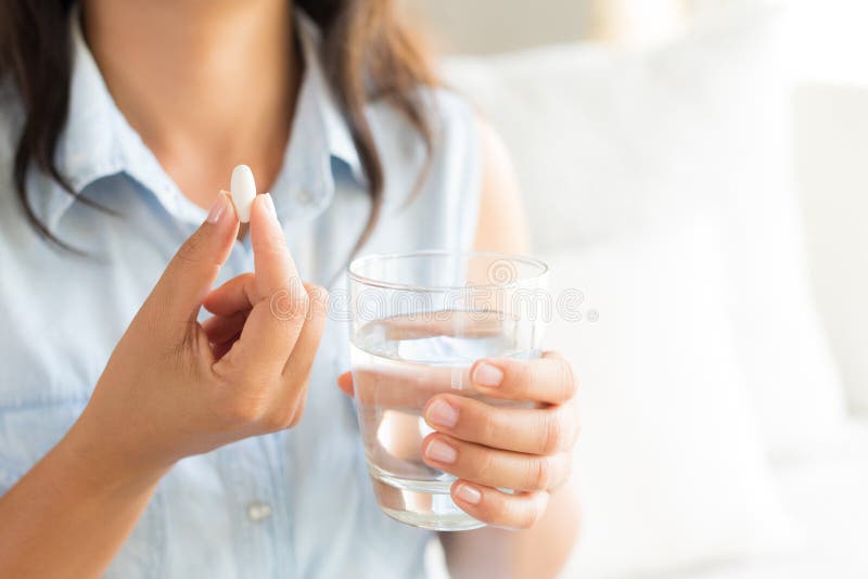 Closeupkvinnahand med preventivpillermedicinminnestavlor och exponeringsglas av wate arkivbilder Closeupkvinnahand med preventivpillermedicinminnestavlor och exponeringsglas av wate arkivbilder
